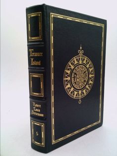 a black book with gold trim on the front and back cover is sitting on a white surface