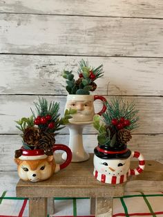 three mugs with plants in them sitting on a table next to a christmas decoration