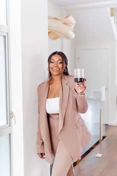 a woman holding a glass of wine in her right hand and smiling at the camera