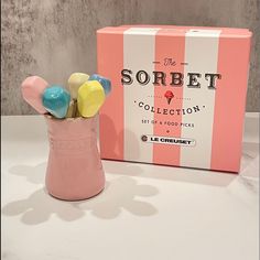 the sorbet collection is in a pink vase next to a box of candy