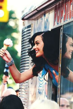 a woman holding an ice cream cone in front of a window with people looking out the window