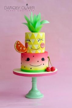 a three tiered cake decorated with pineapples, cherries and a smiley face