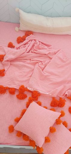 a pink bed with orange pom poms on it