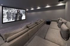 a home theater with two couches and a large screen on the wall behind it