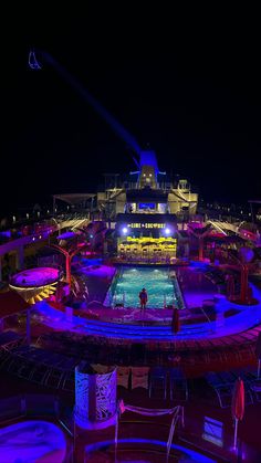 a cruise ship deck at night lit up with neon lights and chairs around the pool