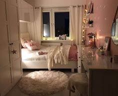 a bedroom with pink walls, white furniture and lights on the window sills