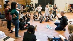 a group of people sitting on the floor in front of a man with a microphone