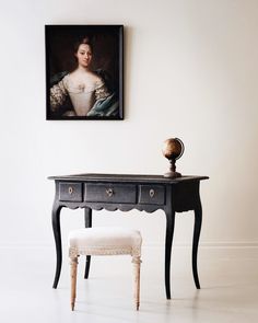 a painting hangs on the wall next to an antique desk