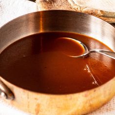 there is a spoon in a pot full of brown liquid on top of the table