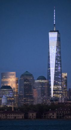 the city skyline is lit up at night, with skyscrapers in the foreground