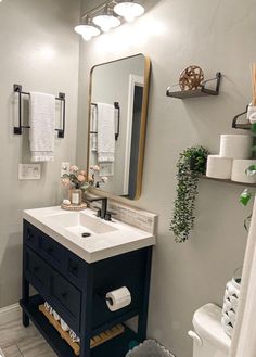 a white toilet sitting next to a bathroom sink under a mirror above a counter top