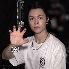 a young man holding his hand up in the air while wearing a white t - shirt