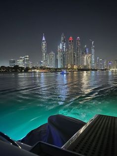 the city skyline is lit up at night as seen from a boat in the water