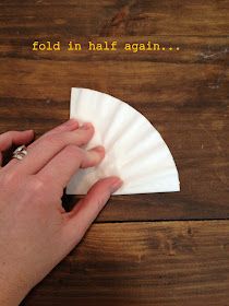 a hand is holding a piece of paper on top of a wooden table that says fold in half again