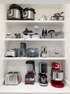 a kitchen shelf filled with appliances and blenders