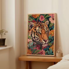 a tiger painting sitting on top of a wooden table next to a bed with white sheets