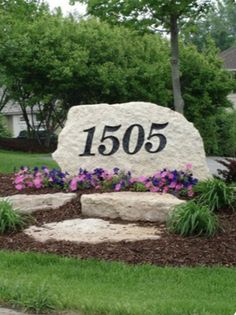 a large stone sign with flowers in front of it and the number 1505 on it