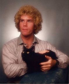 a man with curly hair holding a black cat