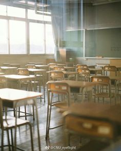 an empty classroom with wooden desks and chairs