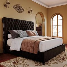 a bedroom with a bed, dresser and mirror in the corner near two arched windows