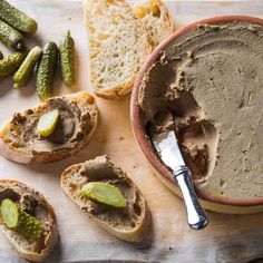 a bowl filled with peanut butter next to bread and pickles