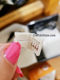 a person holding two small white toothbrushes in their left hand and another one with pink nail polish on it