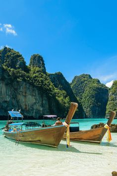 two long boats on the beach with mountains in the background