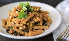 a white plate topped with pasta covered in sauce and garnished with cilantro