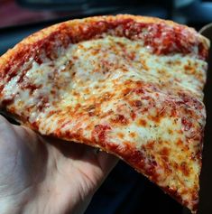 a slice of cheese pizza being held in someone's hand