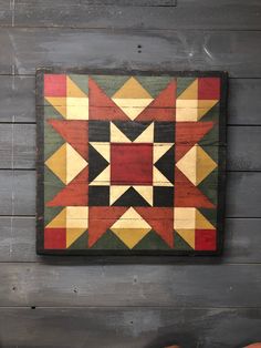 a wooden wall hanging on the side of a building with an old fashioned patchwork pattern