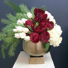 a gold vase with red and white flowers in it