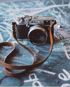 a camera sitting on top of a table next to a brown leather strap with writing on it