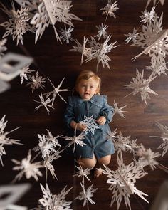 a baby is laying on the floor surrounded by snowflakes