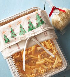 a plastic container filled with pasta next to a bag of bread on top of a blue table