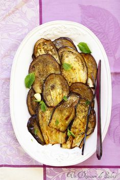 a white plate topped with sliced eggplant on top of a purple table cloth