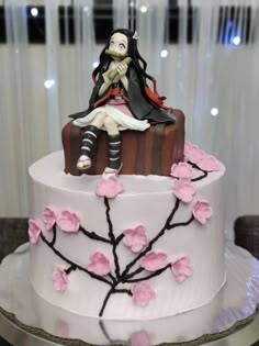 a cake decorated with a woman sitting on top of a suitcase and cherry blossom tree