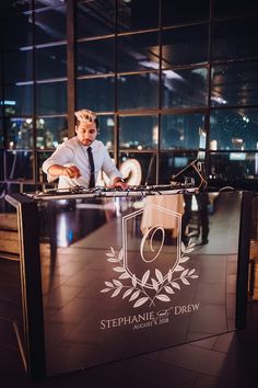 a man in a tie standing at a table with a dj's turntable