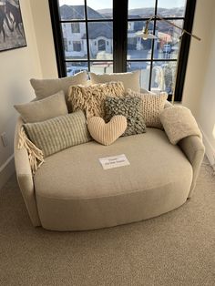 a couch with many pillows on it in front of a window