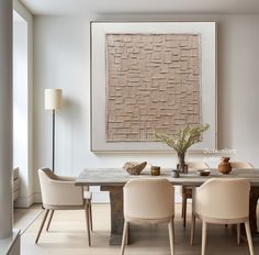 a dining room table with four chairs and a large painting on the wall above it