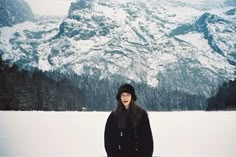 a woman is standing in the snow with her mouth open and mountains in the background