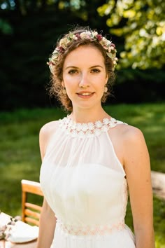 a woman in a white dress is posing for the camera with flowers in her hair