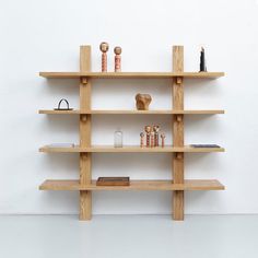 a wooden shelf with various items on it against a white wall in an empty room