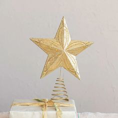 a gold star decoration on top of a white present