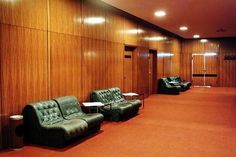 an empty room with leather couches and tables in the center, along with wood paneling