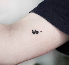 a small black cat tattoo on the arm