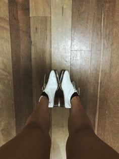 a person wearing white shoes standing on top of a wooden floor with their legs crossed