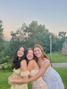 three girls hugging each other in the grass