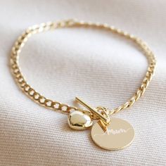 A simple and stylish charm bracelet for everyday wear. This sweet bracelet features a disc charm, personalised with your choice of wording, on a smooth curb chain with an easy to use t-bar and toggle fastening, complete with a small puffed heart charm. Available in silver and gold, it makes a beautiful gift for her. A disc charm will be linked to the necklace and engraved with your personalisation, with space for up to 7 characters. 14ct gold plated brass, sterling silver plated brass Personalised Bracelet, Mom Bracelet, Personalized Leather Bracelet, Cute Couple Gifts, Angel Jewelry, Elephant Bracelet, Moms Bracelet, Charm Necklace Silver, Hand Bracelet