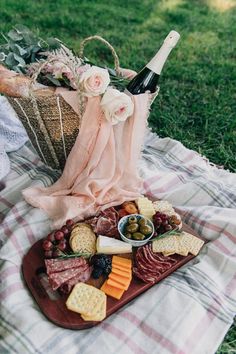 a picnic tray with cheese, crackers, meats and vegetables on a blanket