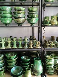 many green bowls and plates are stacked on shelves